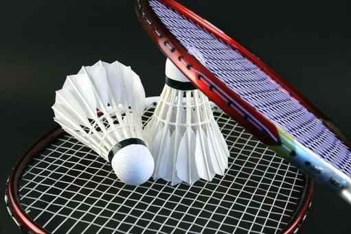 Nahaufnahme eines Badmintonschlägers mit zwei Federbällen auf einem Netz.